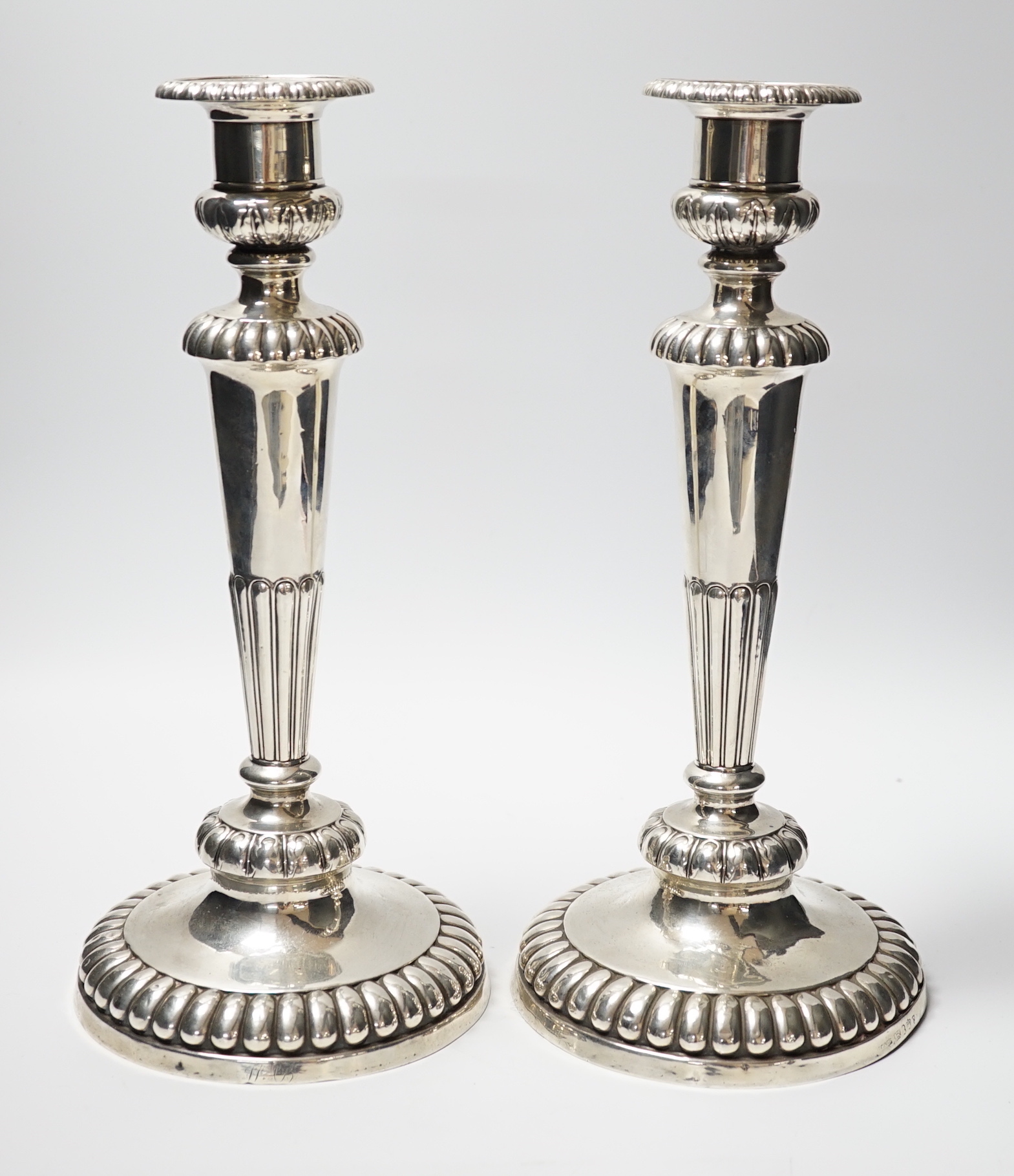 A pair of George III silver candlesticks, on fluted waisted stems, John Roberts & Co, Sheffield, 1811, height 31.6cm, weighted.